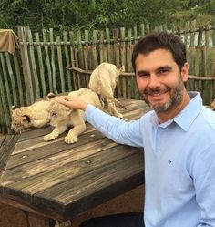 a man sitting at a wooden table with two white lions on it's back