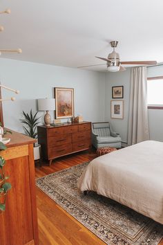 a bed room with a neatly made bed and a chair next to a large window