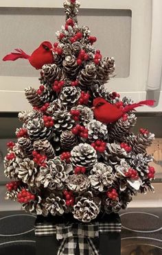 a christmas tree made out of pine cones with red birds sitting on top of it