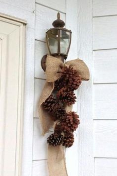 a lantern hanging on the side of a house with pine cones and burlocks