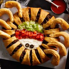 a sandwich made to look like an octopus with tomatoes, lettuce and olives