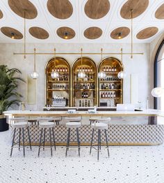 the bar is decorated with gold and white accents, along with four stools in front of it