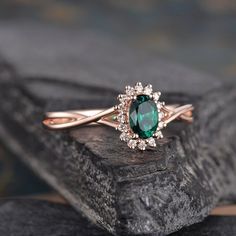 a close up of a ring with a green stone in the center on a rock