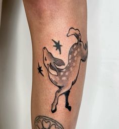 a tattoo on the leg of a person with a deer and stars around her legs