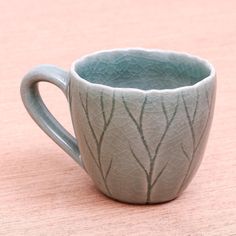 a ceramic cup sitting on top of a wooden table next to a pink wall and floor