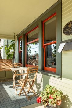 an outdoor patio with chairs and tables on it, next to the front door is a potted plant