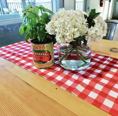 some white flowers are in a vase on a red and white checkered tablecloth