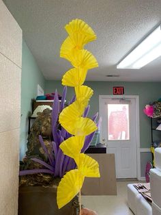 a tall yellow flower sitting in the middle of a living room