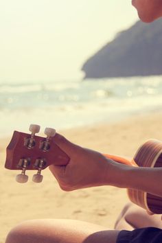 a person playing an acoustic guitar on the beach