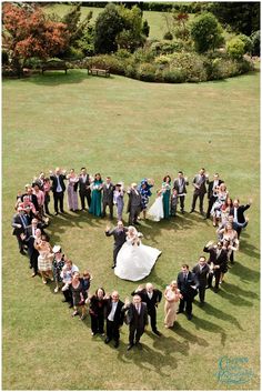 a large group of people standing in the shape of a heart on top of a grass field