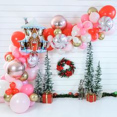 balloons, presents and wreaths are arranged on the wall in front of a christmas themed backdrop