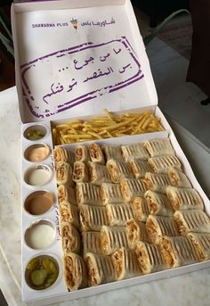 a box filled with food sitting on top of a table next to some dipping sauces