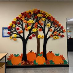 a classroom wall decorated with fall leaves and pumpkins in front of an oak tree