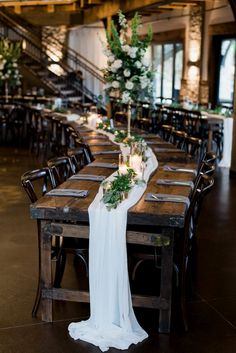 a long table with candles and greenery is set up for an elegant dinner party