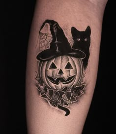 a black cat sitting on top of a pumpkin with a witch's hat over it