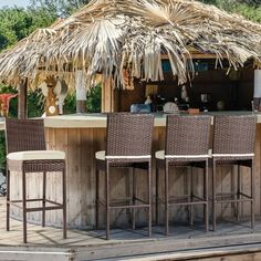 an outdoor bar with wicker chairs and a straw umbrella on the roof, next to a wooden deck