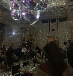 a room filled with people sitting at tables and balloons floating in the air above them