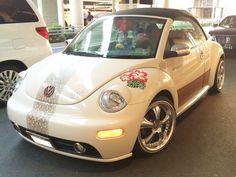 a white car parked in front of a building with flowers on it's side