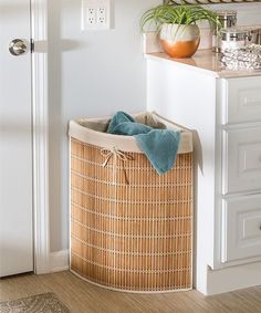 a laundry basket sitting on the floor next to a white cabinet and door with a plant in it