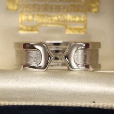 This is a beautiful ring from the luxury jewellery designer Cartier. The ring forms part of the 'Double C' collection and is an iconic and highly recognisable design. The 18ct white gold has a brushed finish in the centre and polished gold borders. Condition: Used (Very Good) Weight: 6.8 grams Ring Size: K 1/2 (50) Band Width: 6.5mm Marked: 'Cartier' '2000' '750' '50' and the serial number Box: Plain gift box Certificate: The Vintage Jeweller guarantee of authenticity If you have any questions r Modern Signet Ring With Round Band For Formal Occasions, Timeless White Gold And Platinum Jewelry, Timeless Platinum Jewelry In White Gold, Timeless Platinum White Gold Jewelry, Elegant Formal Signet Ring With Concave Shape, Classic Silver Platinum Bands, Classic Platinum Band In Silver, Classic Open Band Diamond Cut Jewelry, Elegant Concave Signet Ring For Formal Occasions