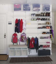 a white closet filled with lots of shoes and backpacks on top of shelving units