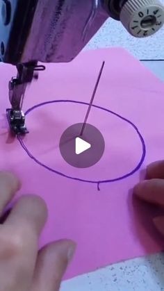 someone is using a sewing machine to sew on a piece of pink paper with purple outline