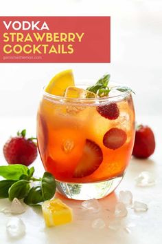 a glass filled with fruit and ice on top of a white table next to strawberries