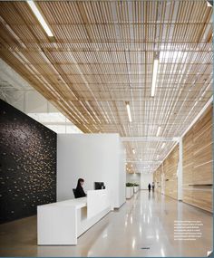 the interior of an office building with white walls and wood ceilinging, along with two people sitting at desks