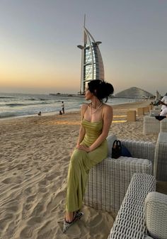 a woman sitting on top of a white couch next to the ocean in front of a tall building