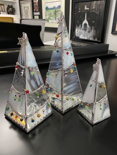 three glass christmas trees sitting on top of a table