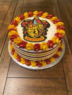 a harry potter birthday cake on a wooden table with the hogwarts crest in red, yellow and orange