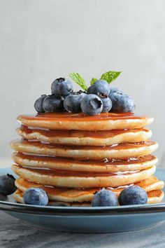 a stack of pancakes topped with blueberries and syrup