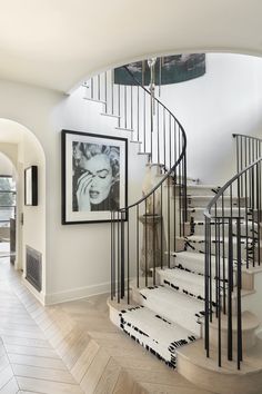 a spiral staircase in a home with pictures on the wall and rugs under it