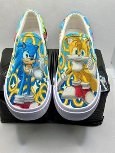 sonic the hedgehog slip on shoes with yellow and blue designs are sitting on top of a black box