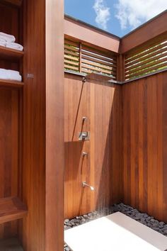 a wooden shower stall with rocks and pebbles in the floor, along with shelves on either side