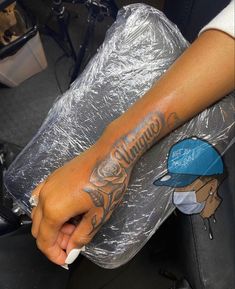 a person with a tattoo on their arm sitting in a chair holding a plastic bag