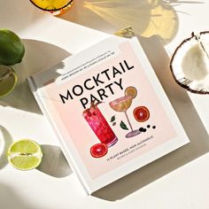 a cocktail party book sitting on top of a table next to limes and other fruit