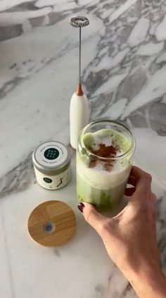 a person holding a cup with some type of drink in it on a marble counter top