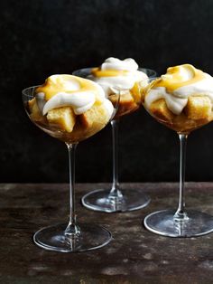 three desserts in wine glasses sitting on a table