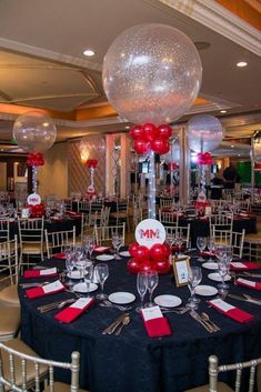 a room filled with tables and chairs covered in red and white balloons, plates and silverware