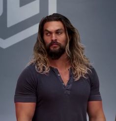 a man with long hair and beard standing in front of a sign that says i love you