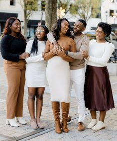 a group of women standing next to each other in front of a tree with their arms around one another