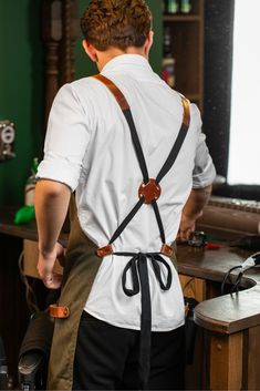 a man with suspenders is standing in front of a desk