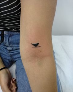 a small bird tattoo on the arm