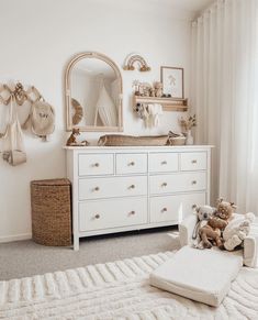 a baby's room with a dresser, mirror and teddy bear