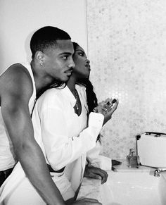 a man and woman brushing their teeth in the bathroom