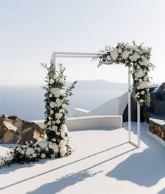 an outdoor ceremony setup with white flowers and greenery