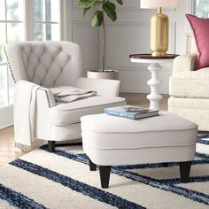 a living room filled with white furniture and a large potted plant in the corner