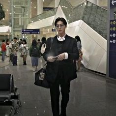 a man in a suit and tie is walking through an airport with his handbag