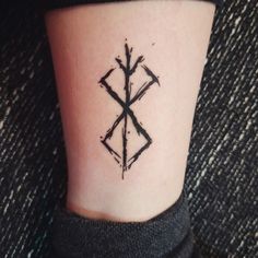 a small tattoo on the ankle of a woman's leg that has arrows drawn across it